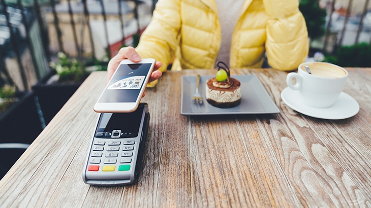 Woman paying for dessert with digital debit card mobile pay.