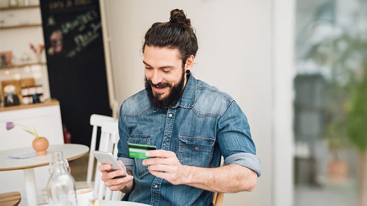 Man making a mobile credit card purchase in a cafe.