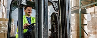 Warehouse worker driving a forklift in a storage room.