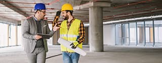 Construction worker and architect talking in building under construction.