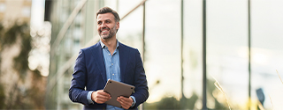 Happy businessman walking outside building.