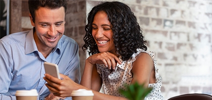 Couple in coffee shop looking at cell phone.