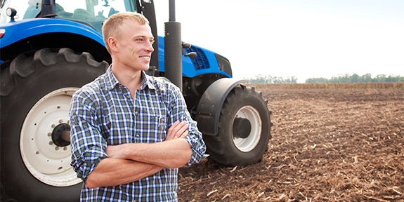 Farmer standing in front of a tractor.
