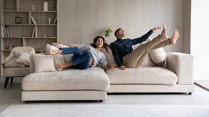Young couple celebrating new house, jumping onto the couch.