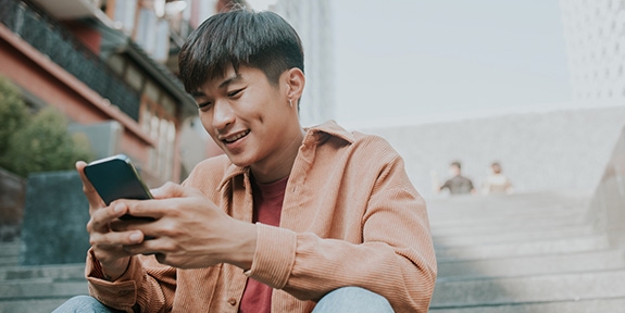 Man sitting on stairs outside using his smartphone.