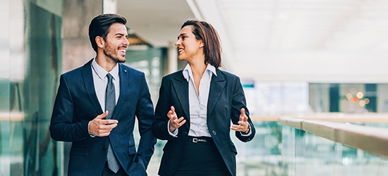 Two business people walking and talking in an office building.