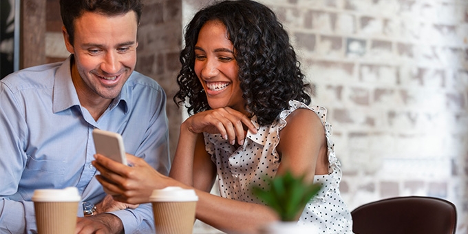 Pareja en la cafetería mirando el teléfono celular.