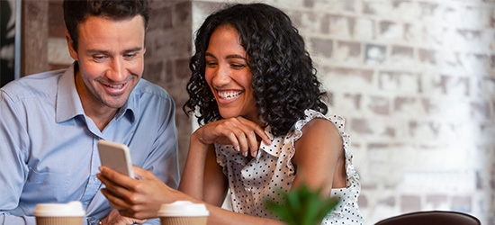 Couple in coffee shop looking at cell phone.