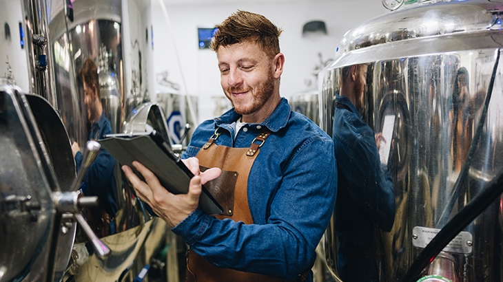 A young businessman in his brewery checking equipment.