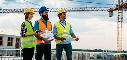 Engineer, architect, and contractor on the construction site with a crane in the background.