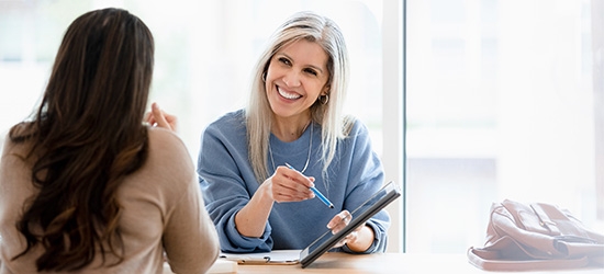 Two businesswomen reviewing a document on a tablet.