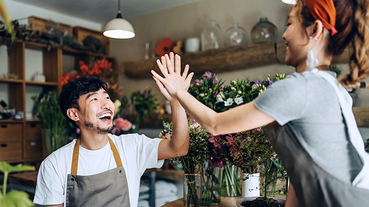 Young business owners of small business flower shop, giving each other a high five.