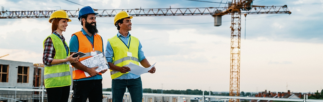 Engineer, architect, and contractor on the construction site with a crane in the background.