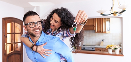 Young couple moving in new house, holding keys.