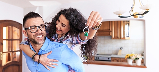 Young couple moving in new house, holding keys.