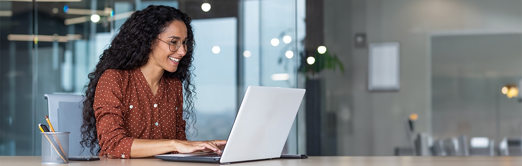 Happy businesswoman in an office working on a laptop.