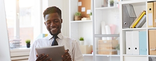 Young businessman with tablet sitting at desk in office.