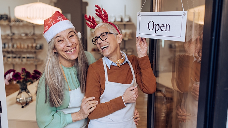 Excited mature women opening their store for the holidays.