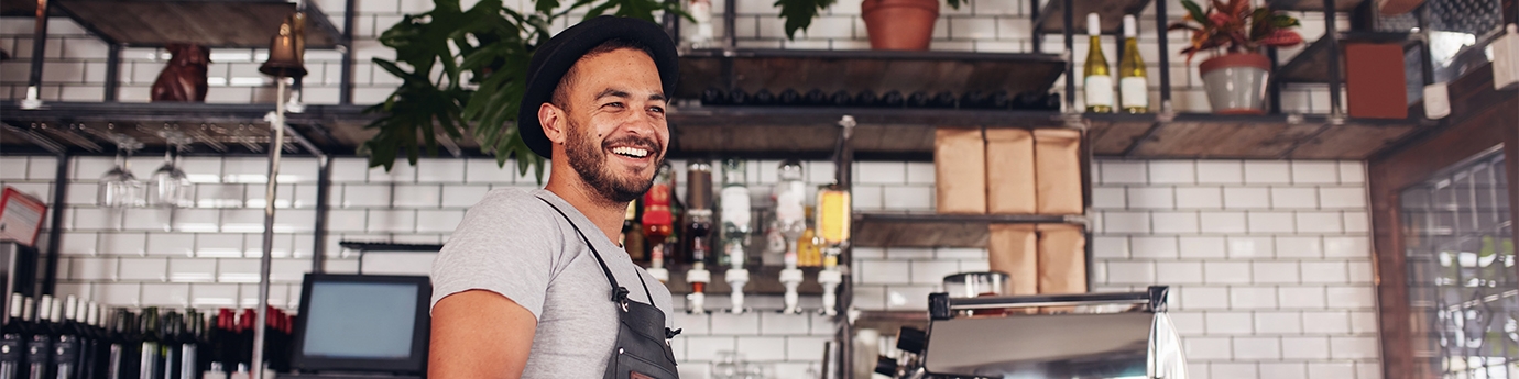 Happy young bar owner standing at the counter.