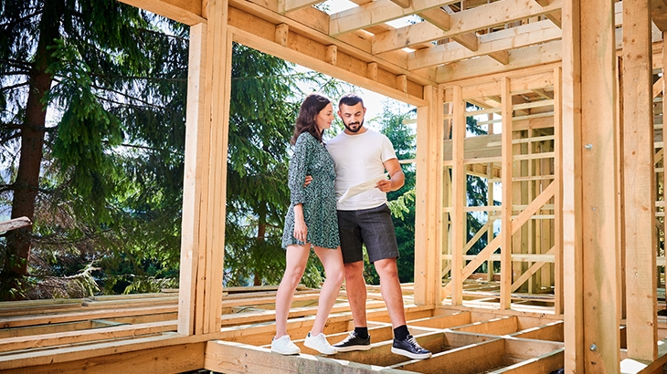 Couple at construction site looking at home building plans.