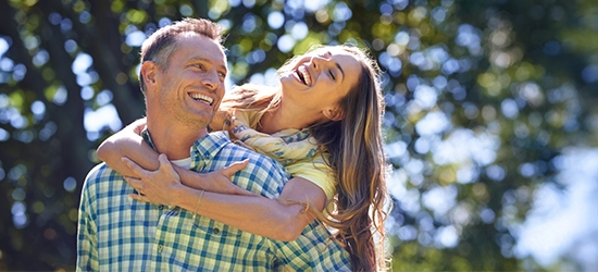Couple laughing outside on a summer day.
