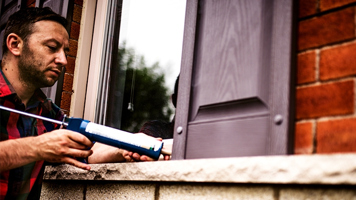 Man applying caulking around a window frame