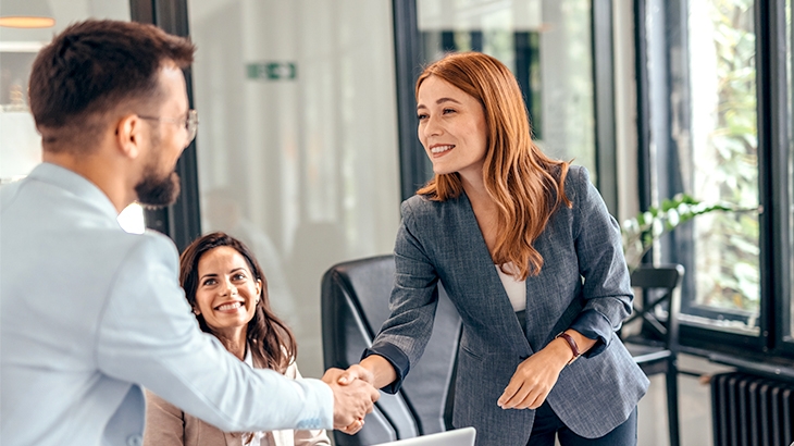 Three professionals in suits shaking hands.