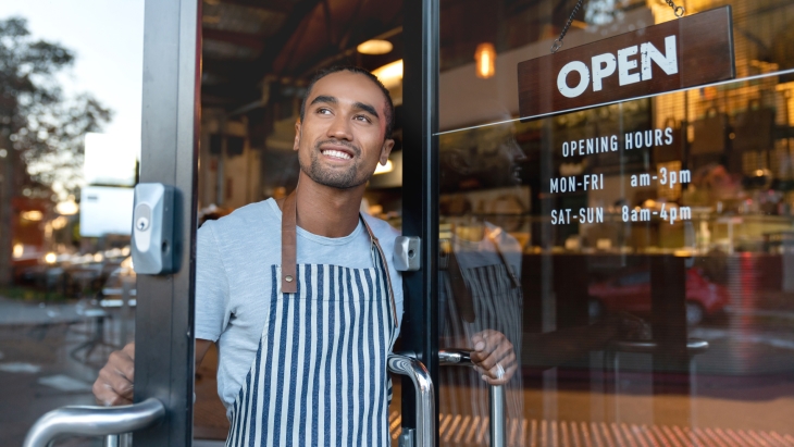 Happy shop owner opening doors at his cafe