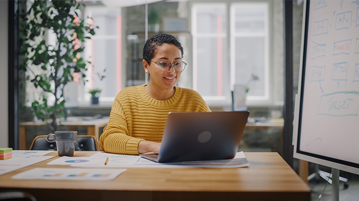 Woman at a desk on laptop crafting a business plan.