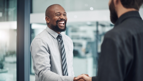 Business partners shaking hands and smiling in the office.