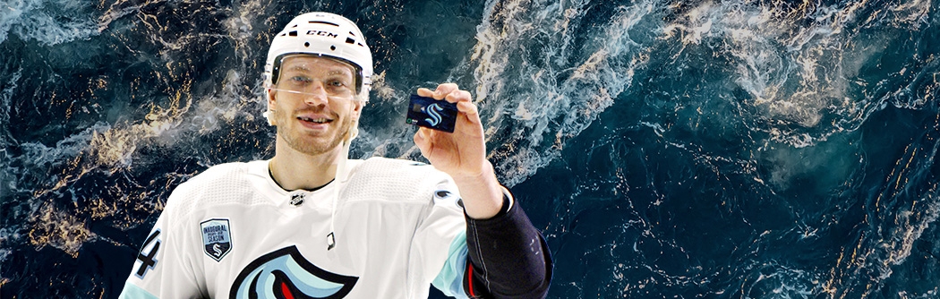 Hockey player holding a WaFd Seattle Kraken debit card.