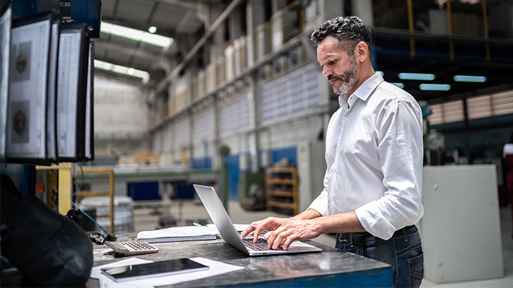 A businessman using laptop in a factory.
