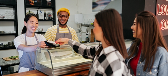 Mujeres realizando un pago de toque con tarjeta de crédito en el mostrador de una tienda.