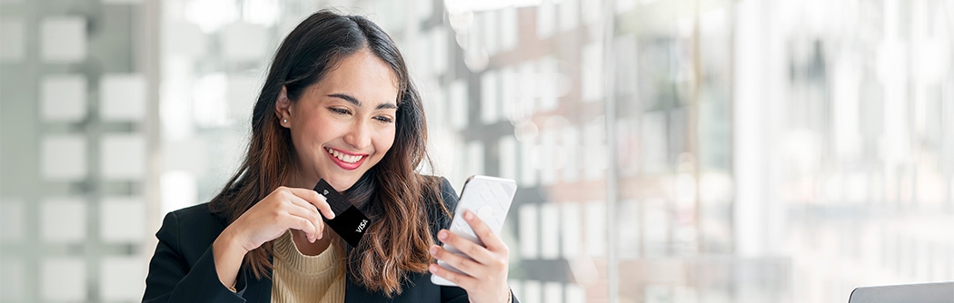 Businesswoman holding WaFd Bank Commercial credit card making a mobile purchase.