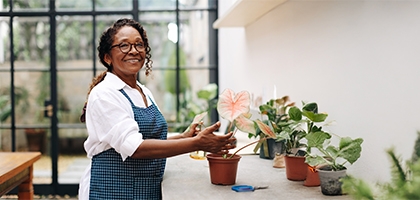 A woman smiling while potting a plant in her shop.