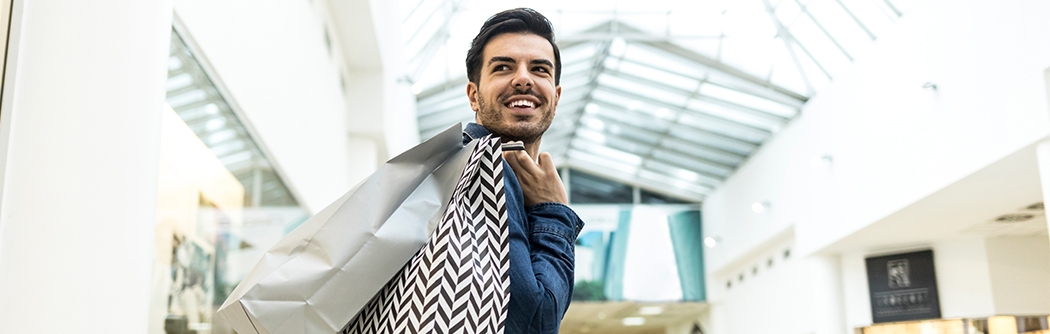 Man walking through a shopping mall with bags.