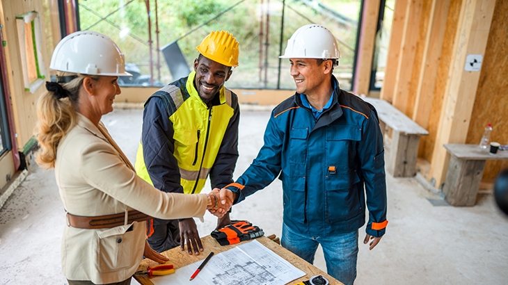Project manager shaking hands with architects in construction site.