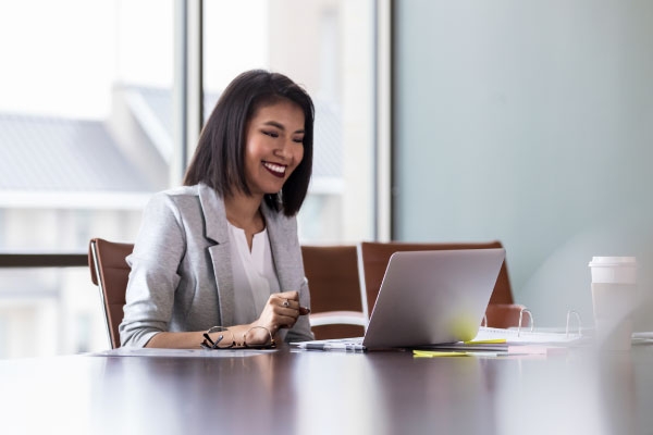 Businesswoman at an office desk looking at laptop and smiling