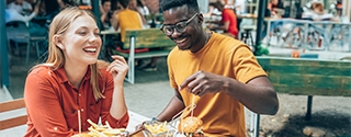 Friends having fun eating burgers and fries at an outdoor restaurant.