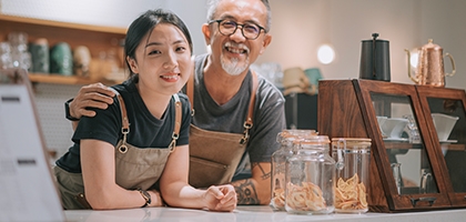 Father and daughter running their cafe, smiling at the counter. 