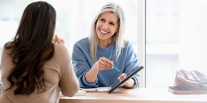 Two businesswomen reviewing a document on a tablet.