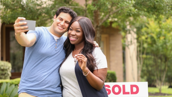 Excited young couple standing in front of new home
