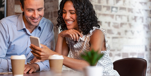 Pareja en la cafetería mirando el teléfono celular.