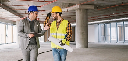 Construction worker and architect talking in building under construction.