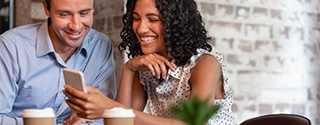 Couple in coffee shop looking at cell phone.