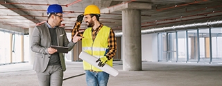 Construction worker and architect talking in building under construction.