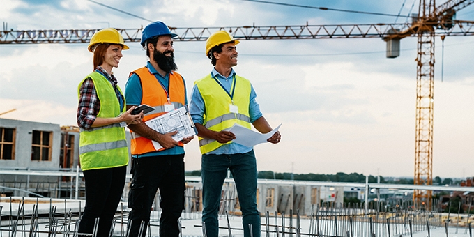 Engineer, architect, and contractor on the construction site with a crane in the background.