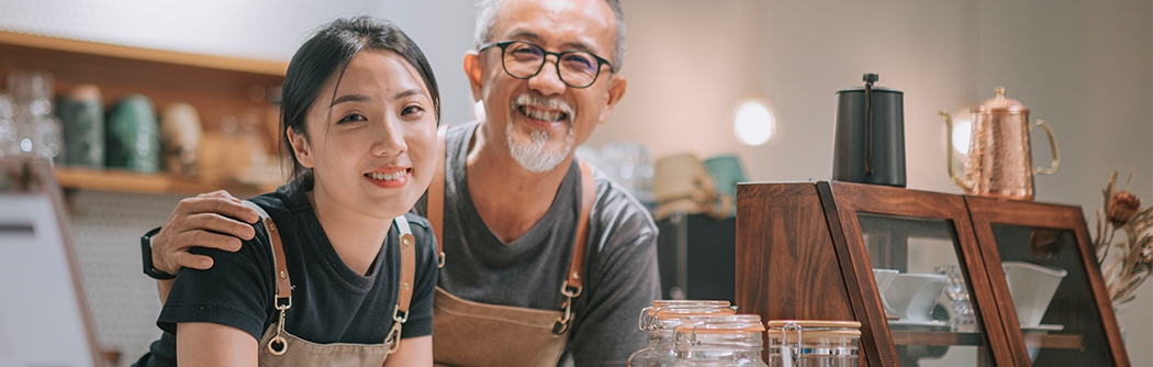Father and daughter running their cafe, smiling at the counter. 