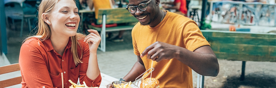 Friends having fun eating burgers and fries at an outdoor restaurant.