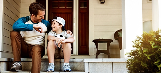 Father and his son laughing and talking on their porch at home.